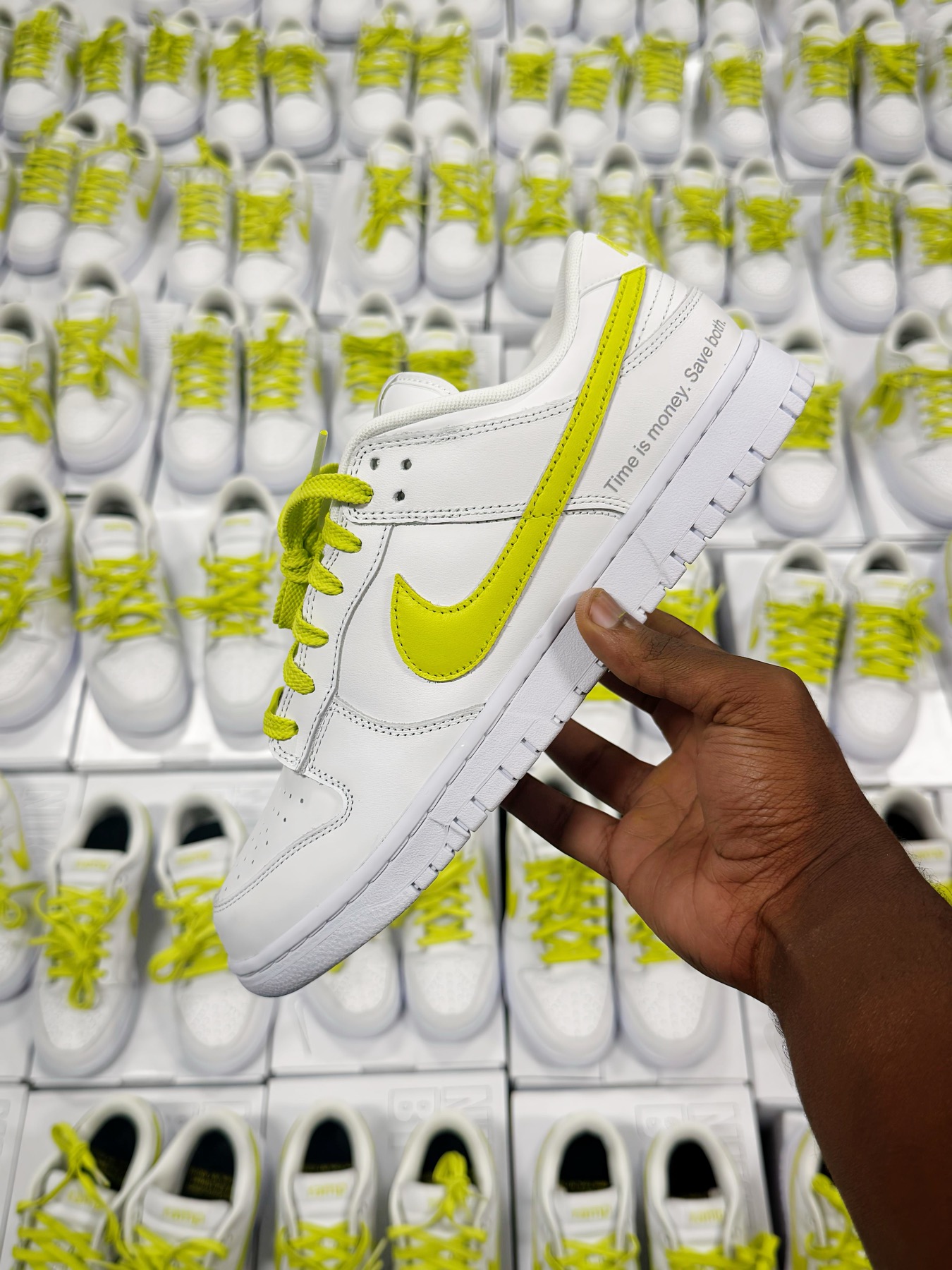 White custom sneaker with lime accents held in front of matching pairs